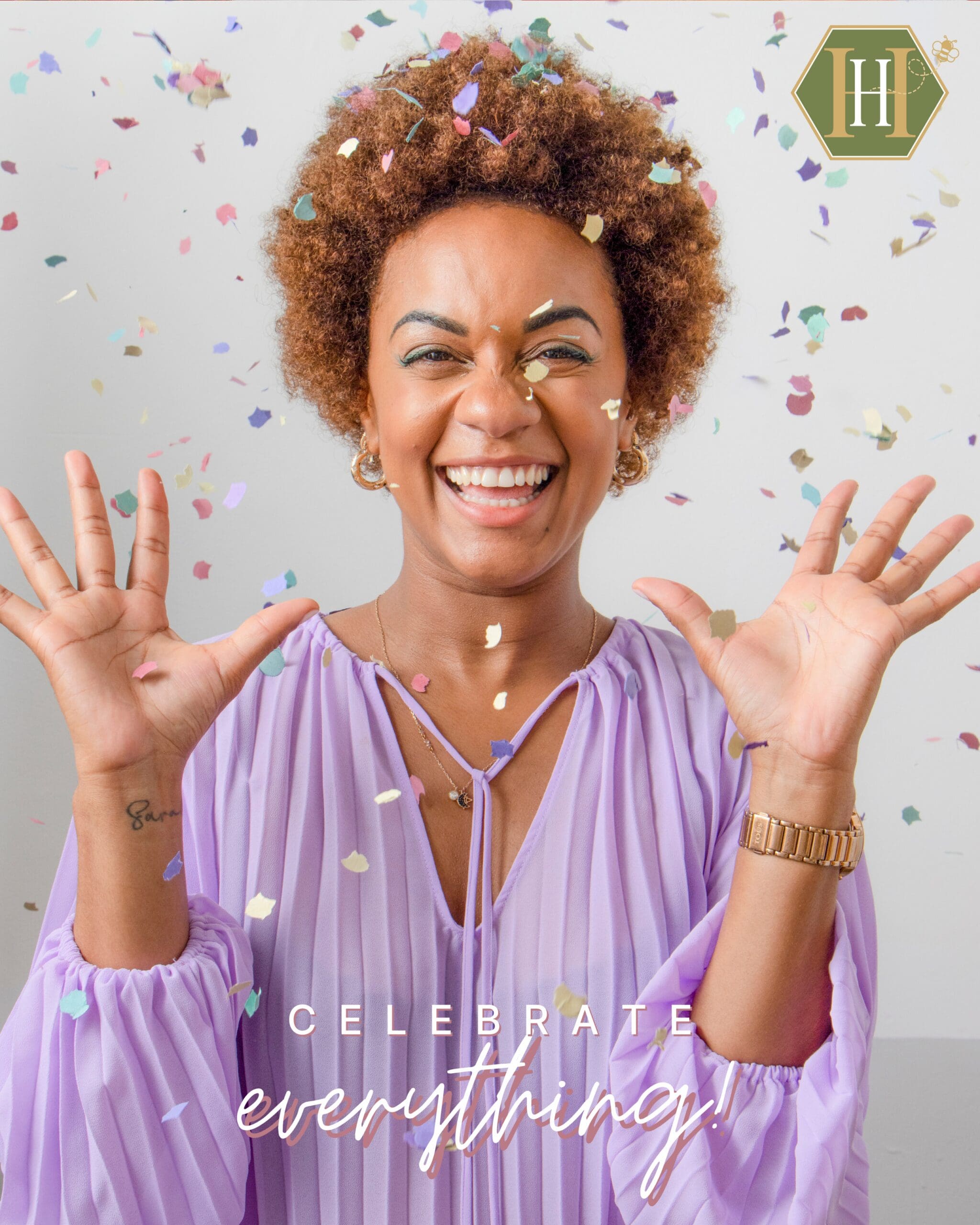 A joyful woman in a lavender blouse smiles widely as colorful confetti falls around her. She raises her hands in celebration. The image includes the Honeycomb Hollow Travel Co. logo in the corner with the text “Celebrate everything!” at the bottom.