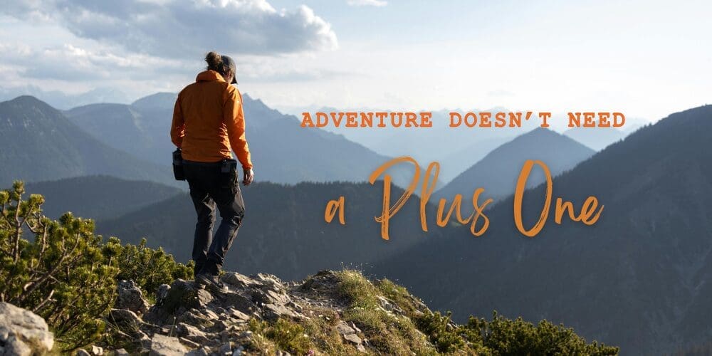 Solo traveler overlooking a mountain landscape with the message, "Adventure Doesn't Need a Plus One," representing the confidence and freedom of solo travel.