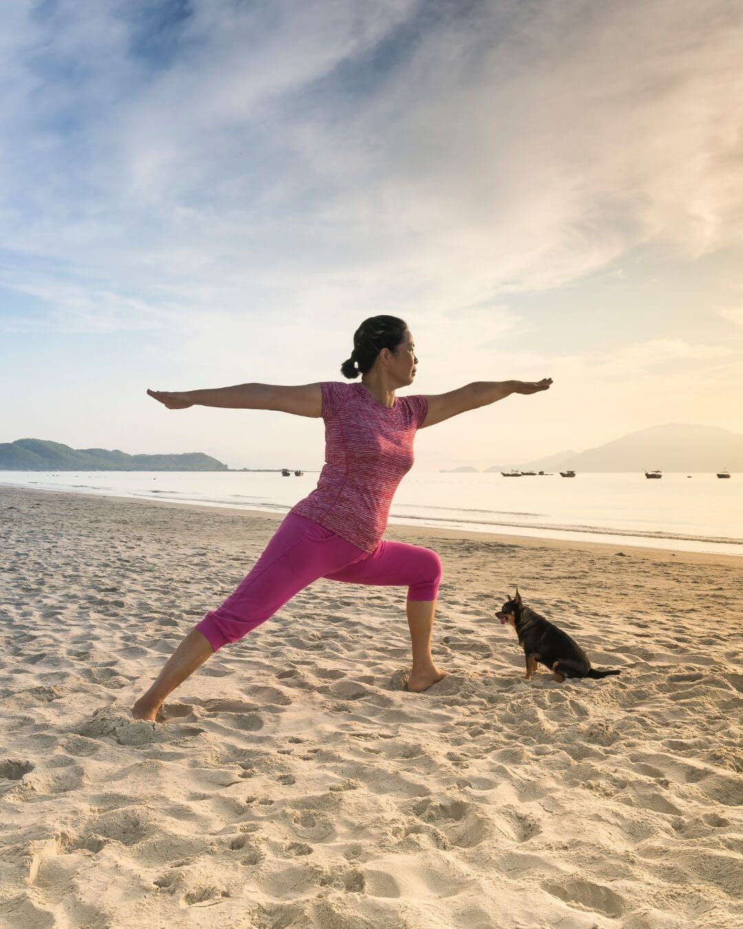 Person practicing yoga on a quiet beach at sunrise, representing wellness travel, mindfulness, and relaxation.